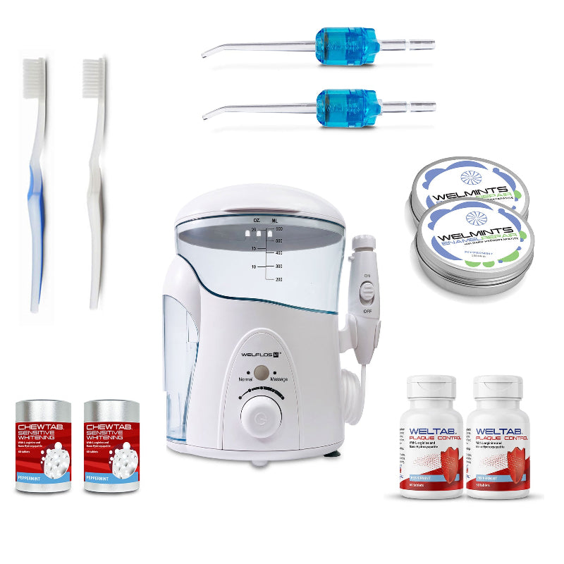 A white oral irrigator water flosser set with a clear water tank, handpiece, toothbrush, two blue Weltips, a small red-and-white bottle,  an aluminum container with mints, and a white-and-red bottle on a plain white background.