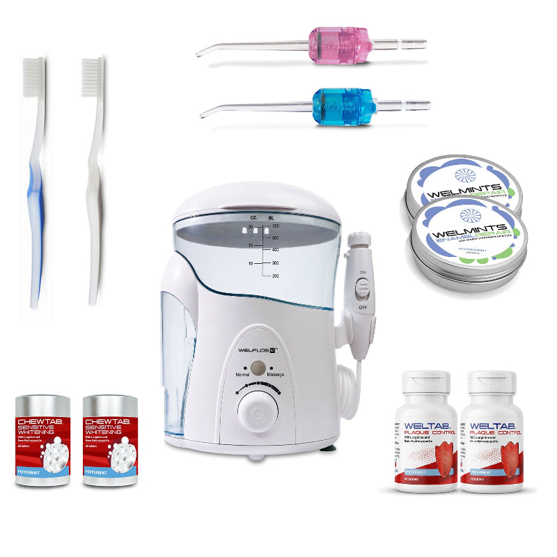 A white oral irrigator water flosser set with a clear water tank, handpiece, toothbrush,  blue Weltip, pink Weltip, a small red-and-white bottle,  an aluminum container with mints, and a white-and-red bottle on a plain white background.