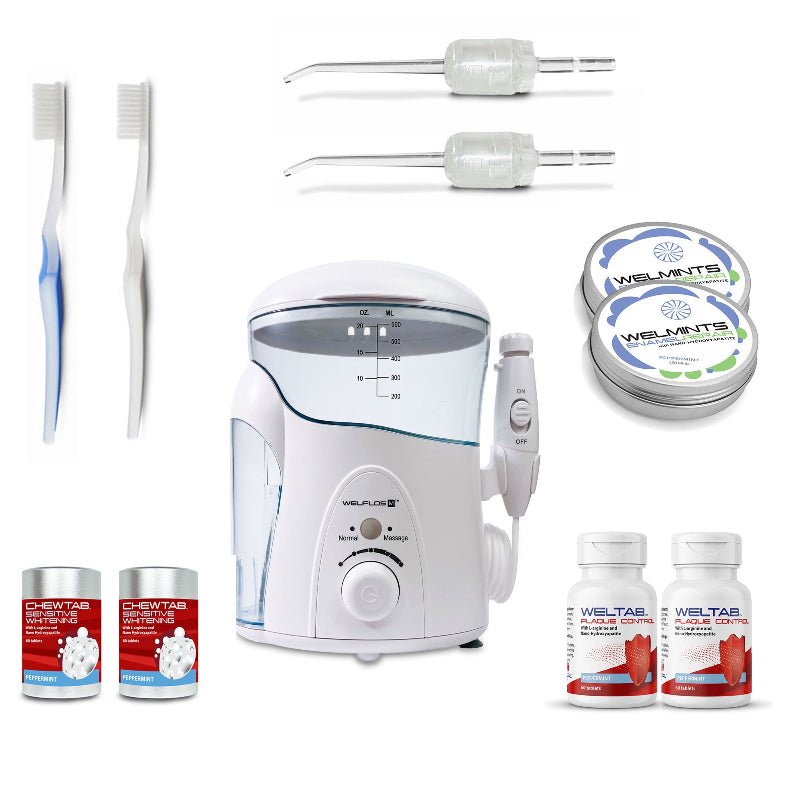 A white oral irrigator water flosser set with a clear water tank, handpiece, toothbrush, two clear Weltips, a small red-and-white bottle,  an aluminum container with mints, and a white-and-red bottle on a plain white background.