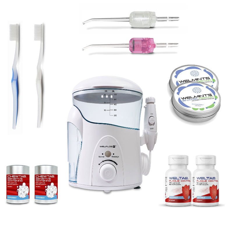 A white oral irrigator water flosser set with a clear water tank, handpiece, toothbrush,  pink Weltip, clear Weltip, a small red-and-white bottle,  an aluminum container with mints, and a white-and-red bottle on a plain white background.