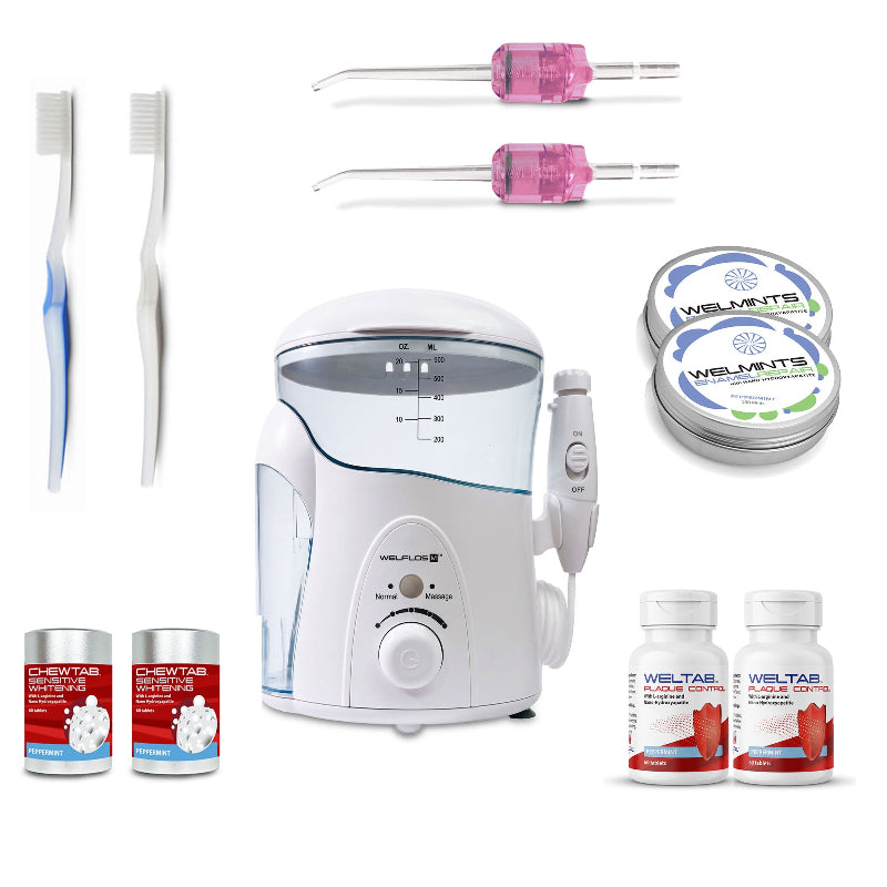A white oral irrigator water flosser set with a clear water tank, handpiece, toothbrush, two pink Weltips, a small red-and-white bottle,  an aluminum container with mints, and a white-and-red bottle on a plain white background.