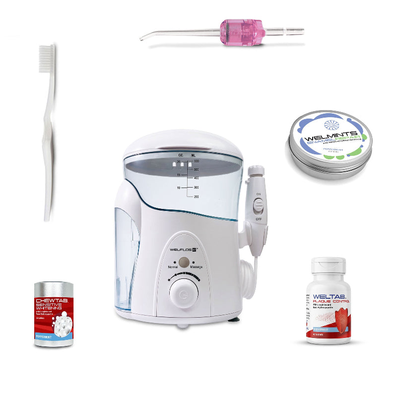 A white oral irrigator water flosser set with a clear water tank, handpiece, toothbrush, a pink Weltip, a small red-and-white bottle,  an aluminum container with mints, and a white-and-red bottle on a plain white background.