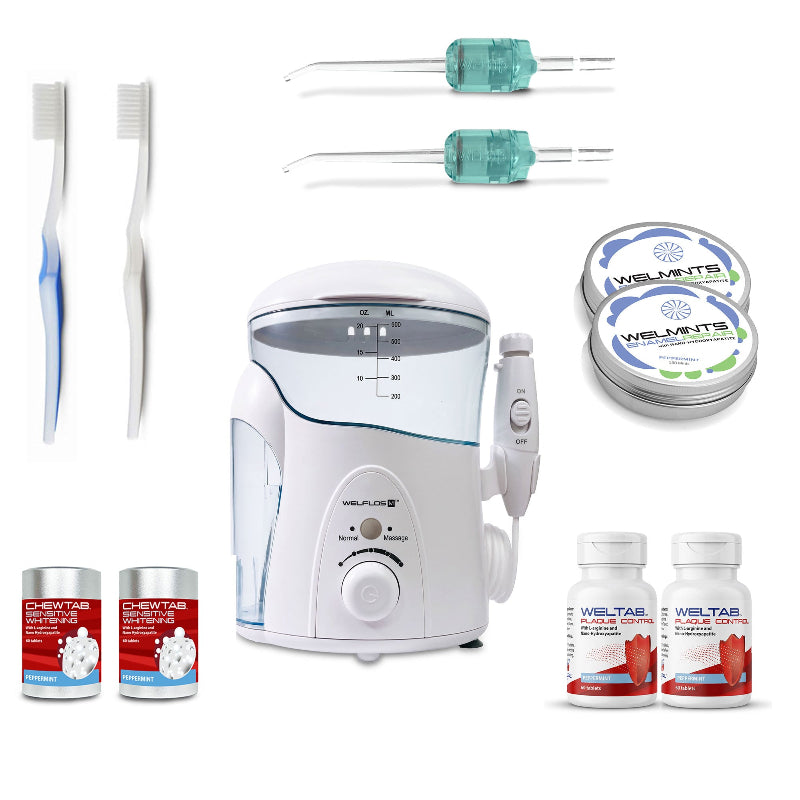 A white oral irrigator water flosser set with a clear water tank, handpiece, toothbrush, two seafoam Weltips, a small red-and-white bottle,  an aluminum container with mints, and a white-and-red bottle on a plain white background.