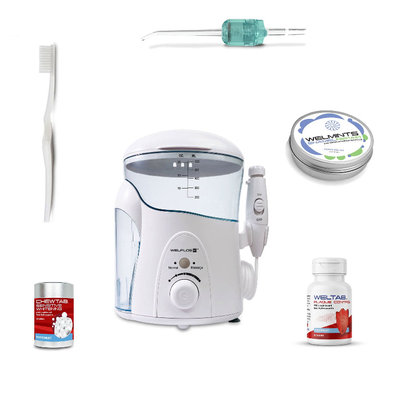 A white oral irrigator water flosser set with a clear water tank, handpiece, toothbrush, a seafoam Weltip, a small red-and-white bottle,  an aluminum container with mints, and a white-and-red bottle on a plain white background.